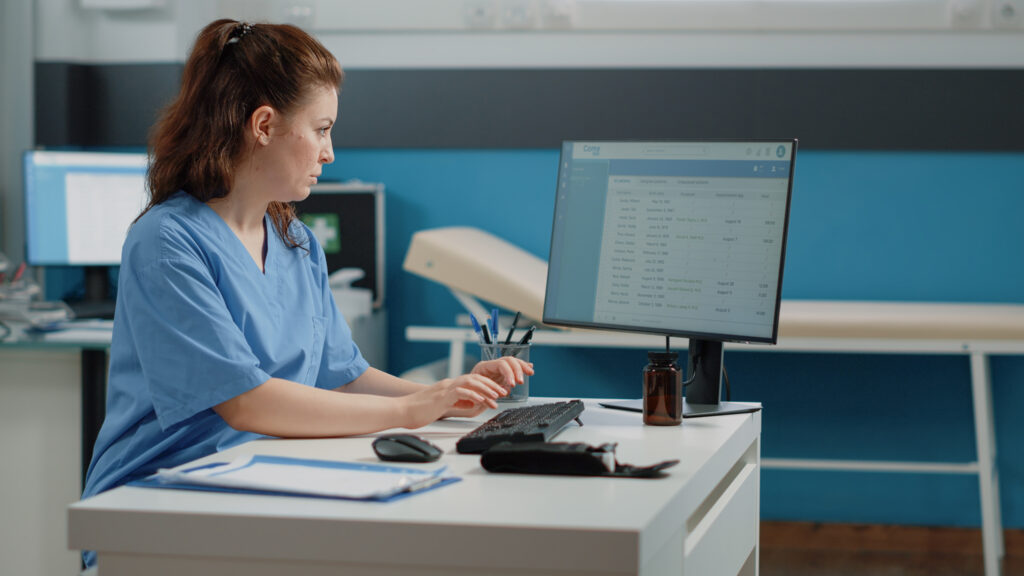 Medical billing specialist reviewing patient claims and denial codes on computer